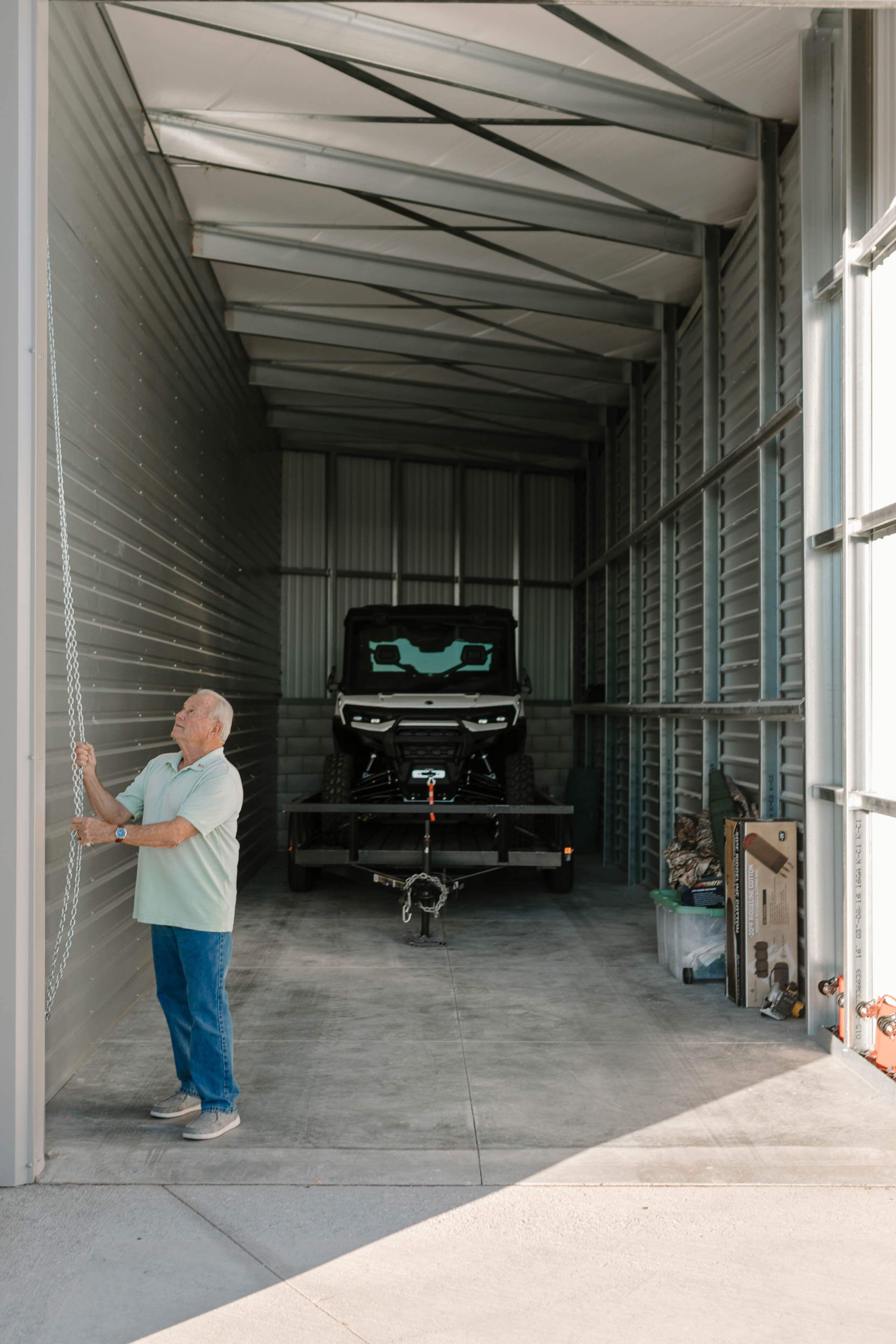 Man opening storage unit with UTV on trailer inside South Meadows